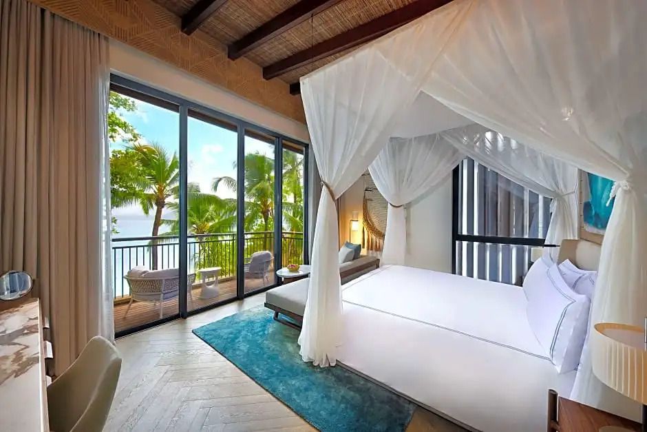 Geräumiges Zimmer mit Himmelbett und großer Glasfront mit Meerblick