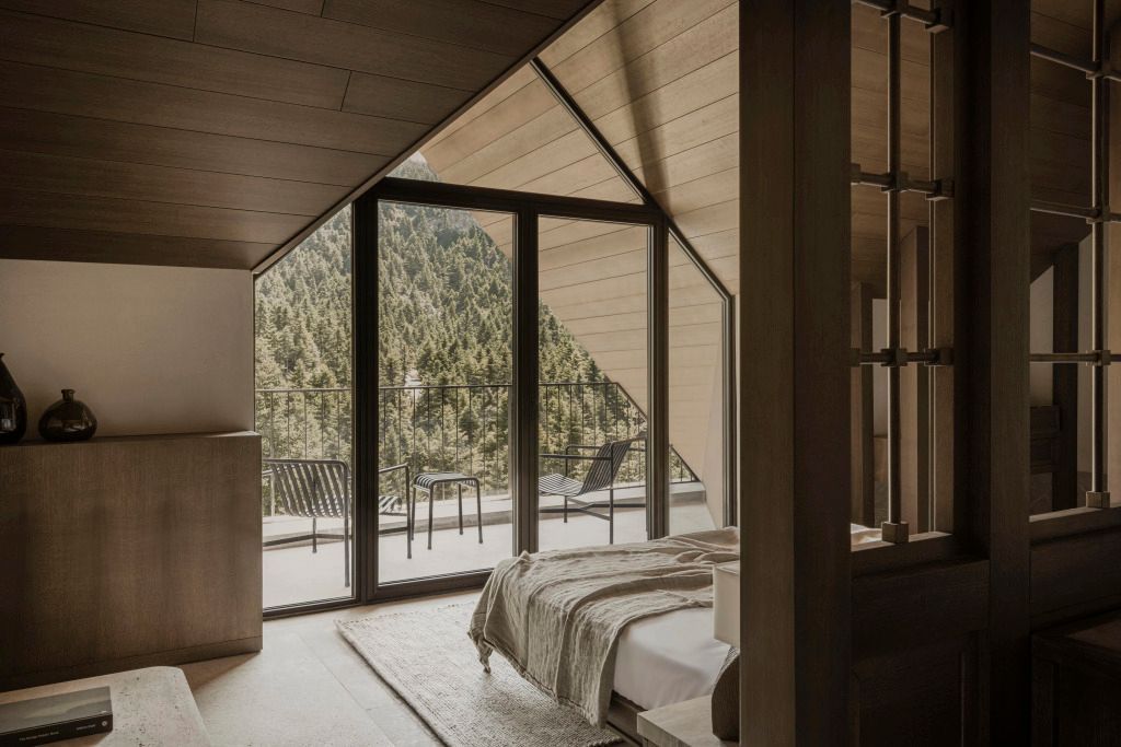 Junior-Suite mit modernem Interieur und Blick auf bewaldete Berge vom Balkon
