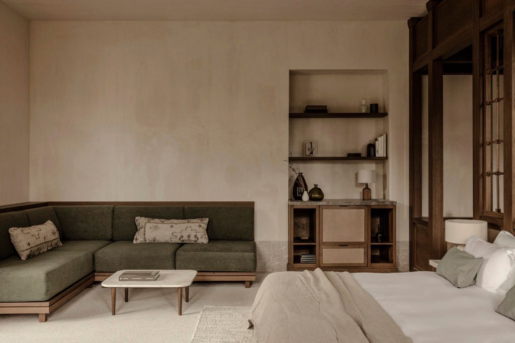 Elegante Suite mit grüner Couch, hellem Tisch und stilvollen Regalen.