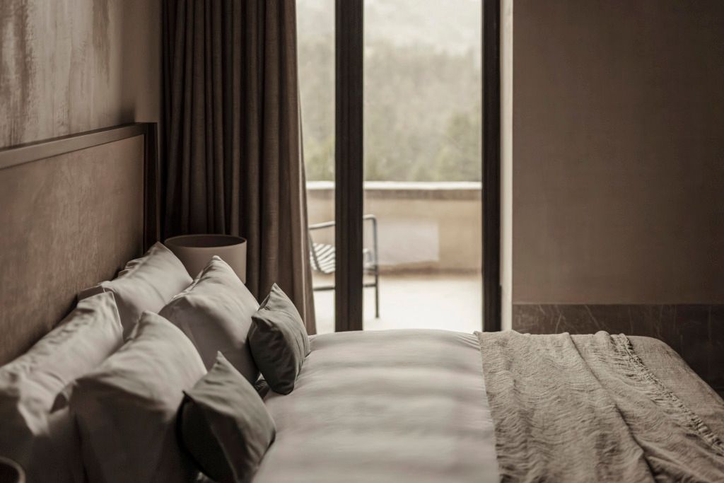 Elegantes Hotelzimmer mit Blick auf die Berge und zwei grauen Kissen auf dem Bett
