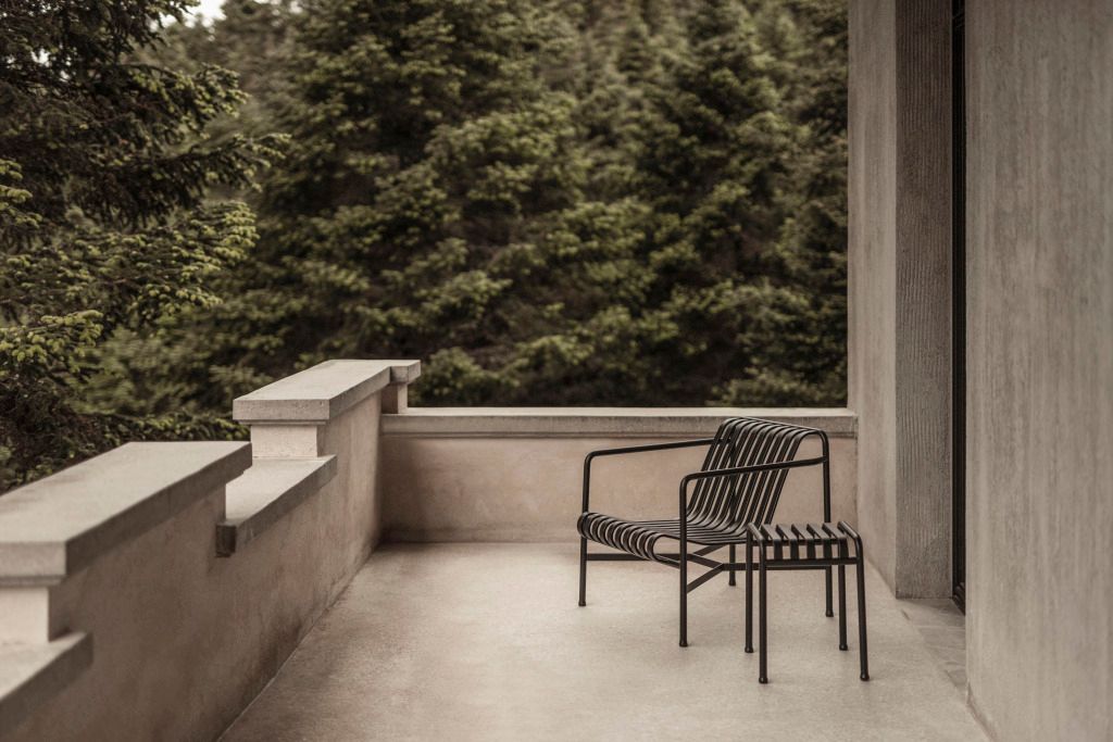 Privater Balkon mit zwei schwarzen Stühlen und Aussicht auf grüne Kiefernwälder
