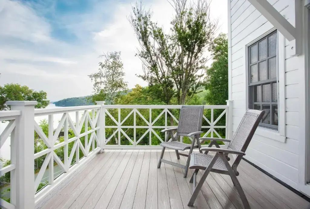 Balkon mit zwei Stühlen und Blick auf bewaldete Landschaft und See