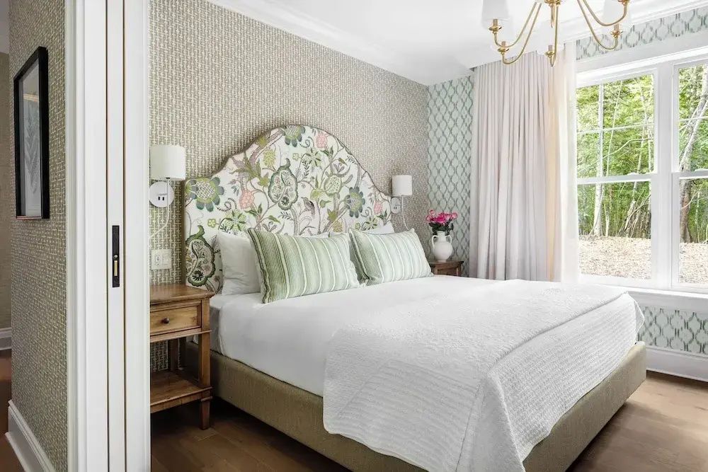 Schlafzimmer mit Doppelbett, geblümtem Bettkopfteil und eleganter Dekoration