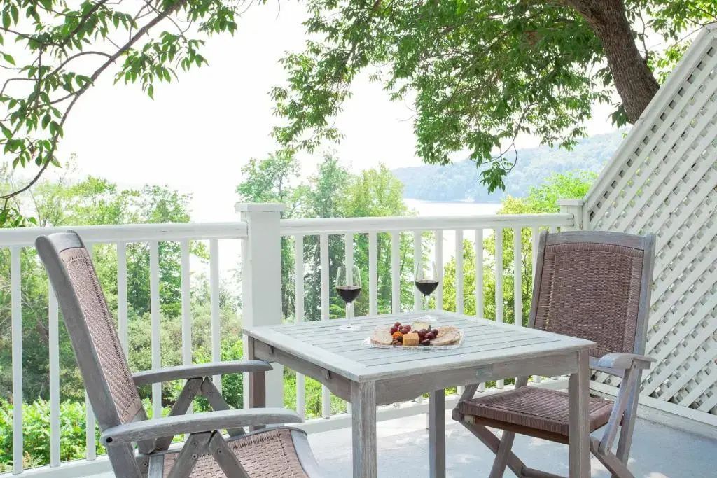 Private Terrasse mit Sitzgelegenheit und Blick auf See mit zwei Weingläsern