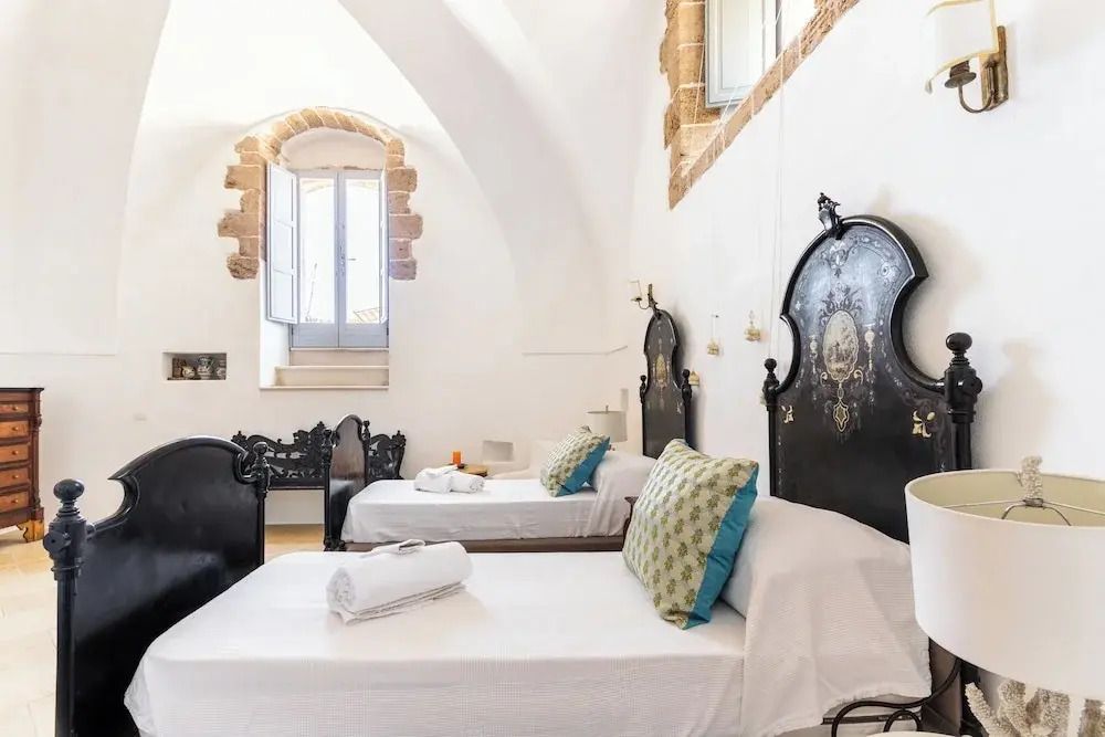 Elegantes Doppelzimmer mit dekorativen Metallbetten und Natursteinakzenten.