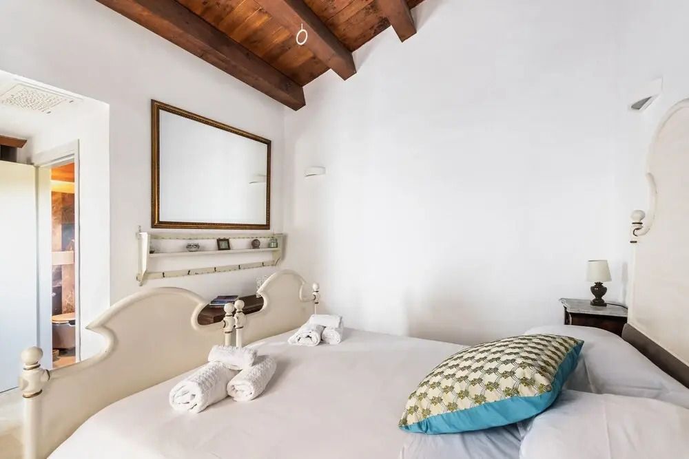 Weißes Bett mit hölzerner Decke und modernem Spiegel in einem eleganten Zimmer