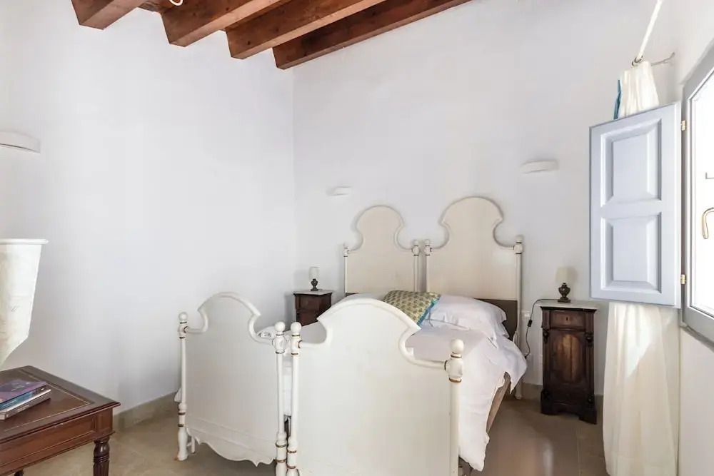 Elegantes weißes Bett mit hölzerner Decke und rustikalen Nachttischen