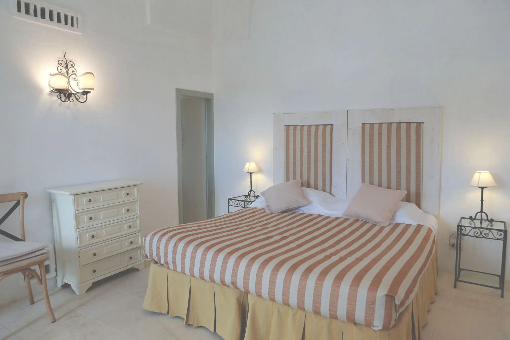 Gemütliches Schlafzimmer mit gestreiftem Bett und klassischer Kommode