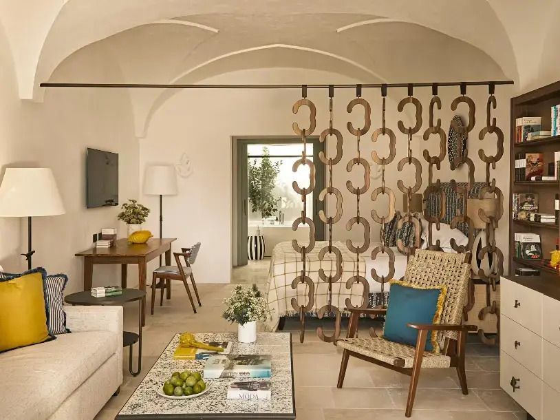 Gemütliche Suite mit luxuriöser Sitzecke und dekorativer Raumtrennung im Hotel Rocco Forte Masseria Torre Maizza.