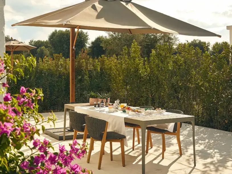 Einladender Außenbereich mit gedecktem Tisch und Sonnenschirm umgeben von blühenden Pflanzen.