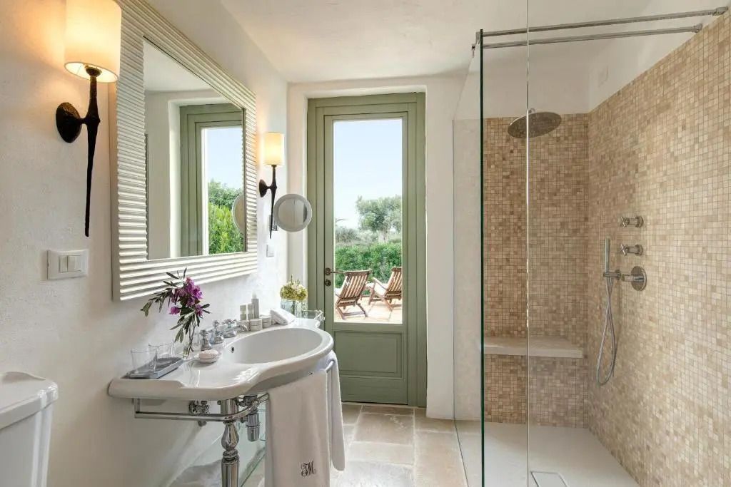 Helles Badezimmer mit Glasdusche, großem Waschbecken und Zugang zur sonnigen Terrasse.