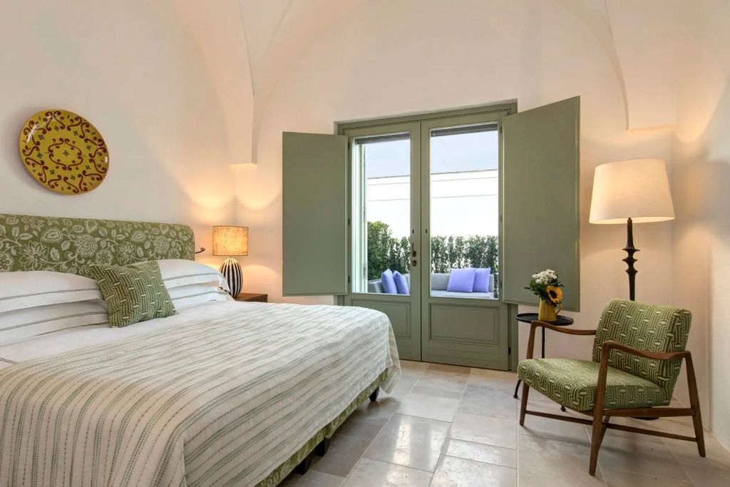 Elegantes Schlafzimmer mit Doppelbett und Ausblick auf Terrasse im Rocco Forte Masseria