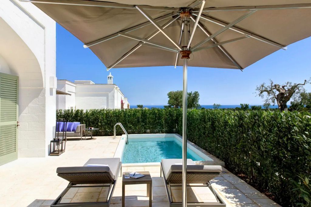 Privater Poolbereich mit Liegestühlen und Sonnenschirm mit Blick auf das Meer