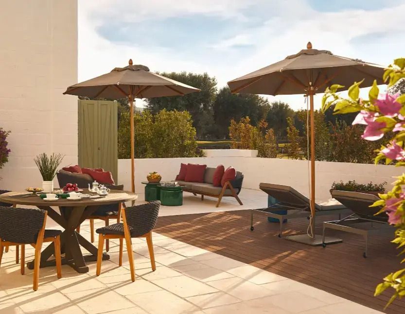 Terrasse mit Sitzbereich und Sonnenschirmen in grüner Umgebung