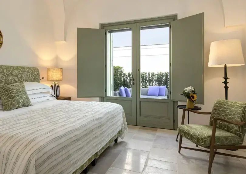 Helles Schlafzimmer mit großem Fenster, das auf eine Terrasse führt