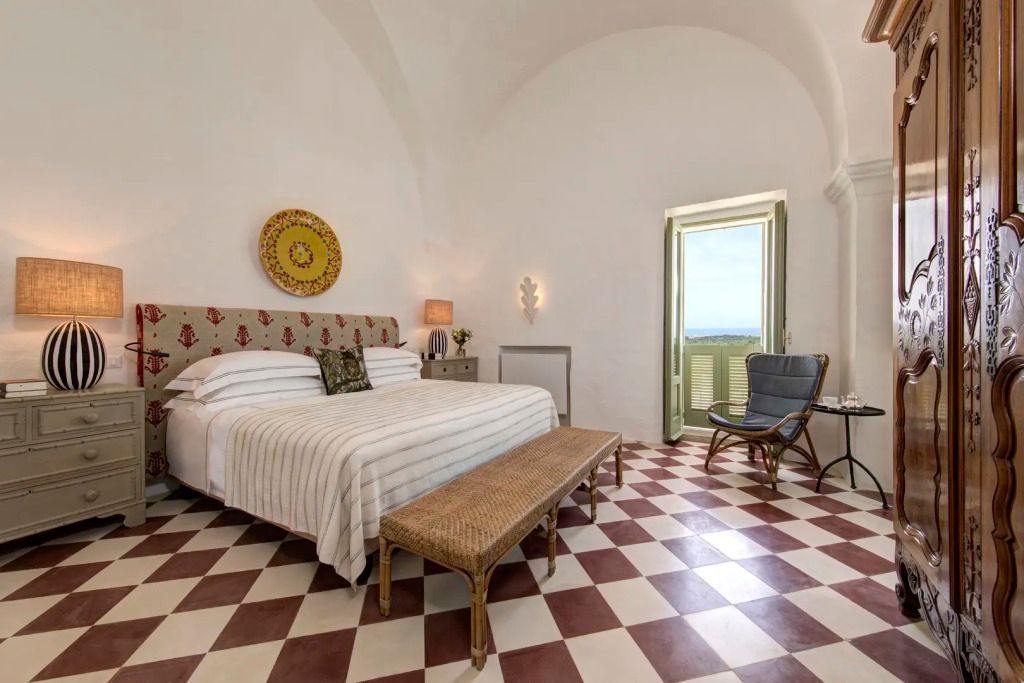 Schlafzimmer mit Doppelbett und traditionellen Fliesen in der Torre Suite mit Blick ins Grüne.