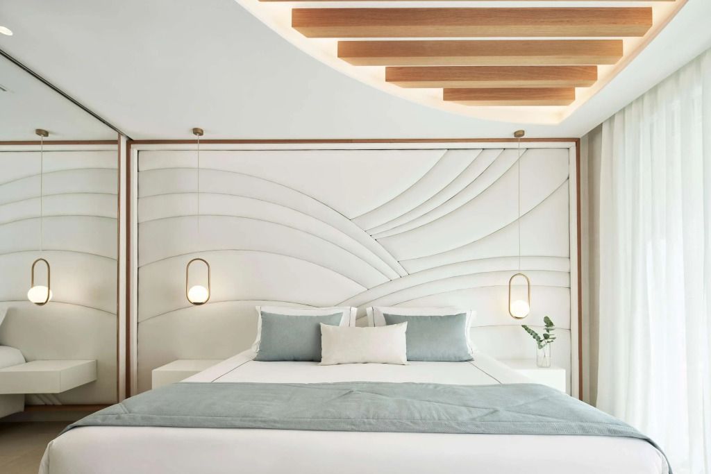 Elegantes Doppelbett mit modernen Hängelampen und kunstvoller Wandverkleidung