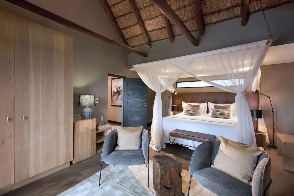 Luxus-Schlafbereich mit Himmelbett und modernen Sitzmöbeln im afrikanischen Stil
