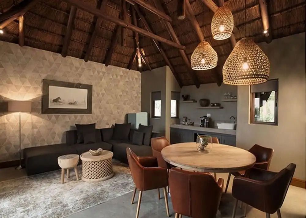 Wohnzimmer mit rustikalem Strohdach, Holz-Esstisch und gemütlicher Sitzecke