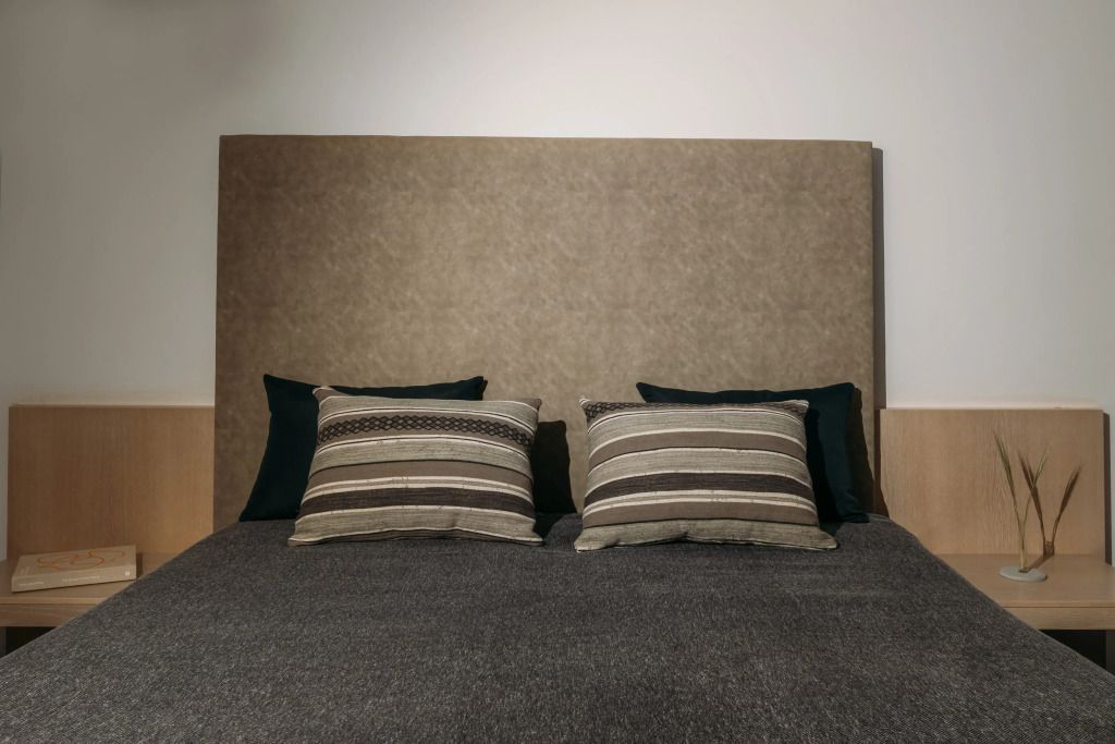 Modernes Doppelbett mit gestreiften Kissen und neutralem Farbschema
