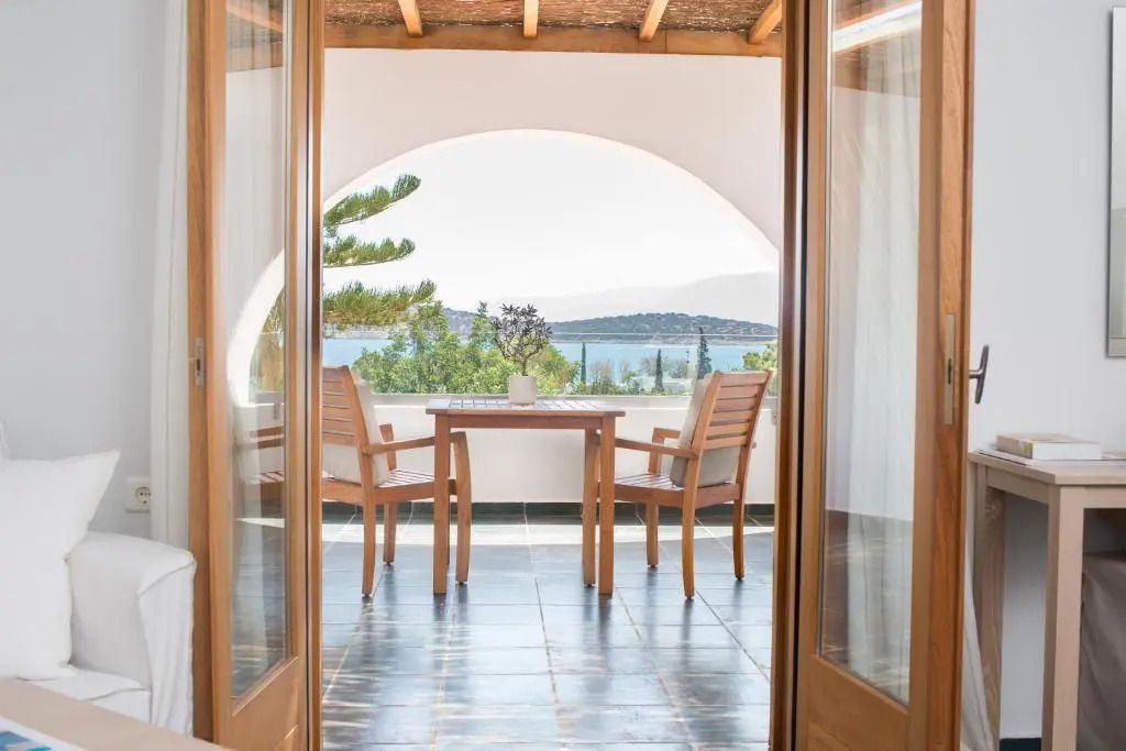 Holzmöbel auf einem Balkon mit Blick auf das Meer und bewaldete Hügel