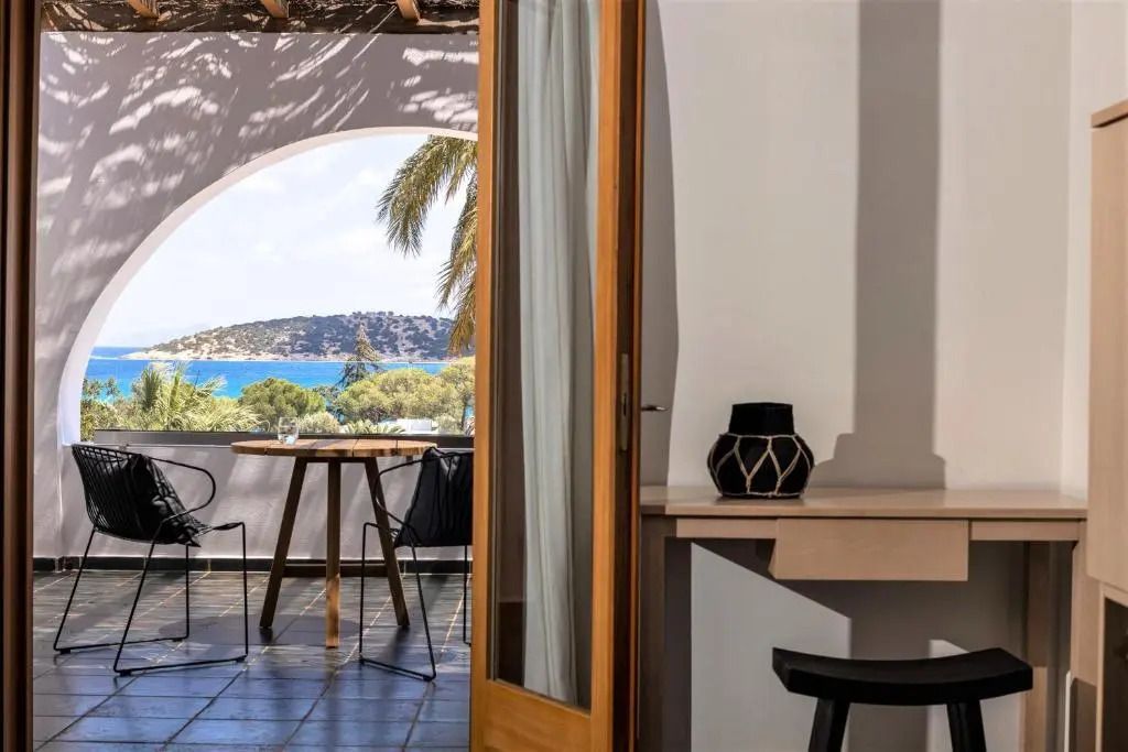 Glastüren öffnen sich zu einem Balkon mit Meer- und Palmenblick