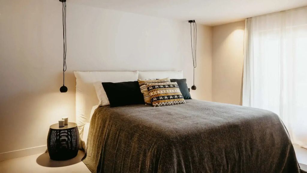 Modern eingerichtetes Schlafzimmer mit großem Doppelbett und dekorativen Kissen