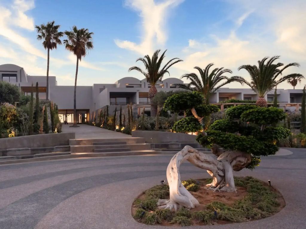 Eleganter Eingang zum Hotel Minos Palace mit Palmen und geschwungenen Wegen