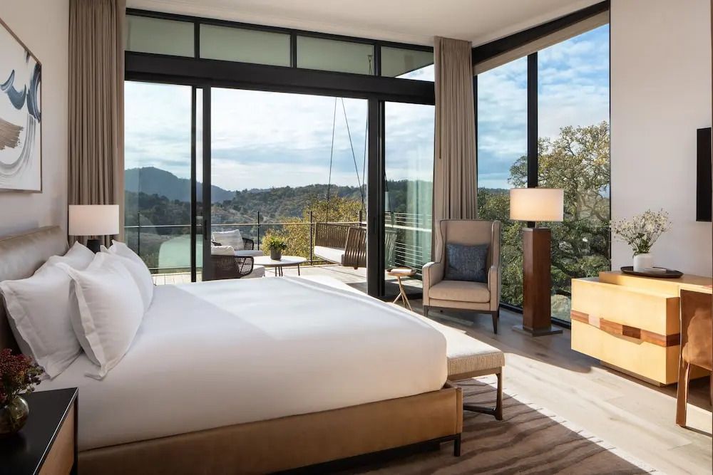 Helles Zimmer mit Balkon und Blick auf bewaldete Hügel