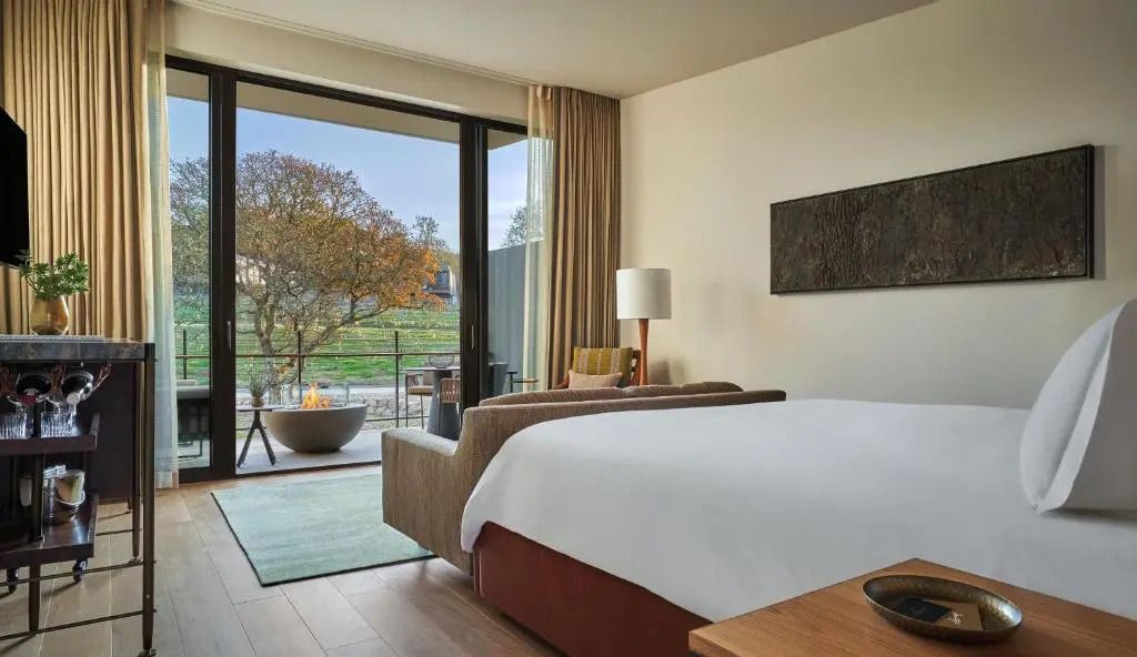 Geräumiges Hotelzimmer mit großem Bett und Aussicht auf Garten