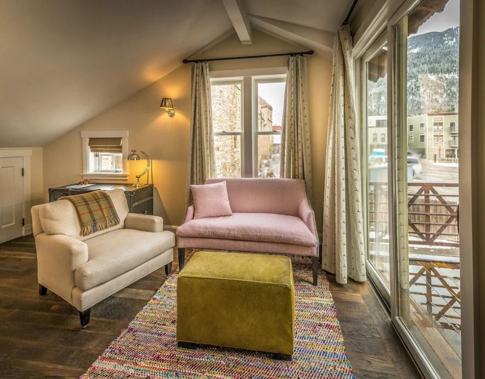 Gemütlicher Sitzbereich mit zwei Sofas, farbigem Teppich und Fensterblick.