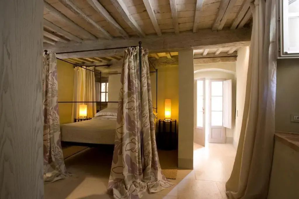 Gemütliches Schlafzimmer mit Himmelbett und Holzbalkendecke. Warmes Licht und elegante Vorhänge.