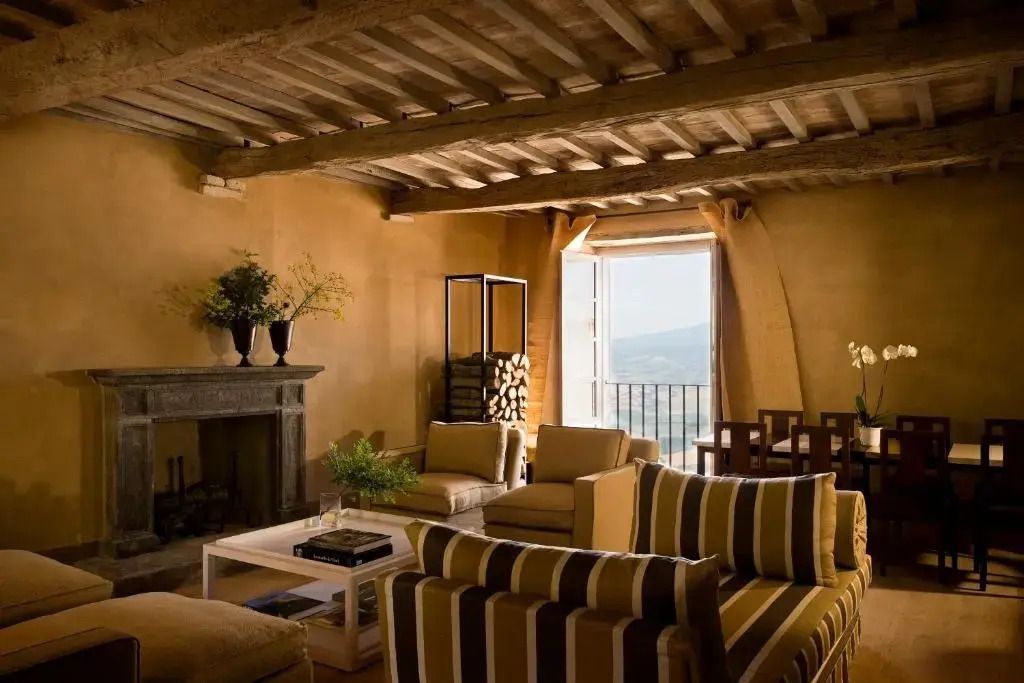 Elegantes Wohnzimmer mit Kamin, bequemen Sofas und direktem Blick auf die toskanische Landschaft.