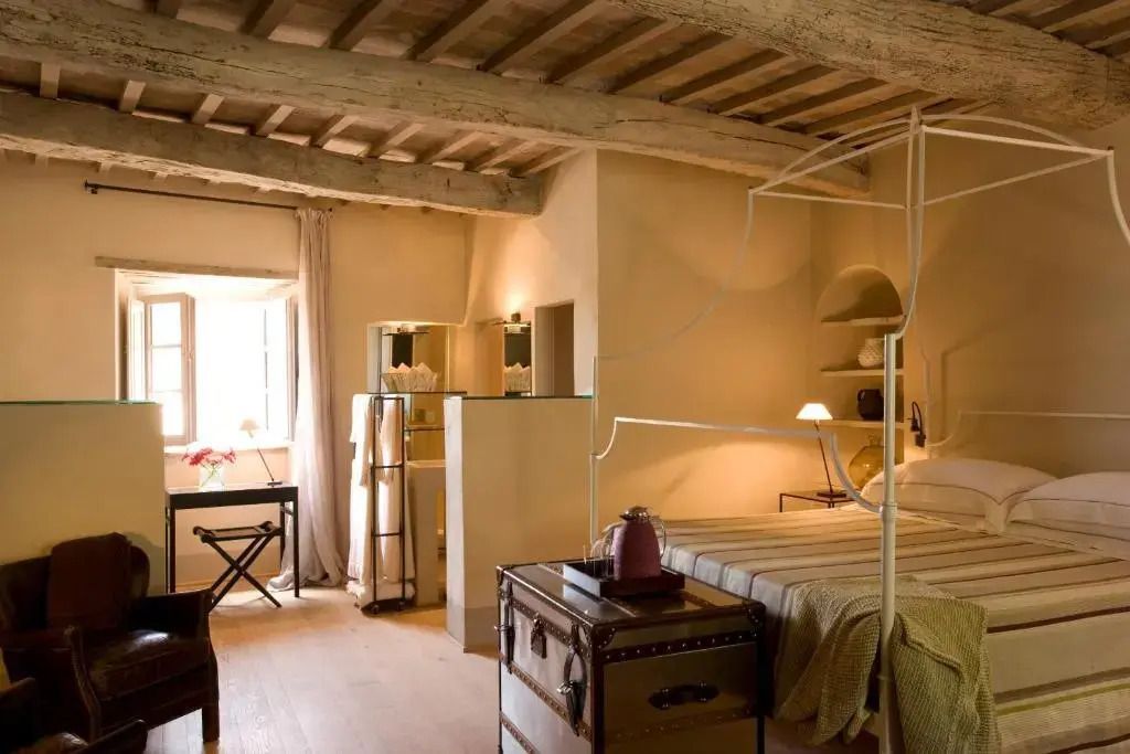 Geräumiges Schlafzimmer mit stilvollem Bettgestell, Holzbalkendecke und natürlichem Licht.
