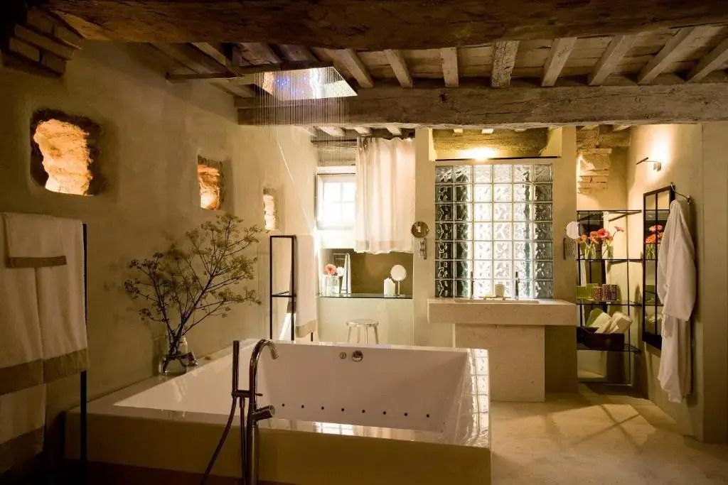 Luxuriöses Badezimmer mit großer Badewanne, Holzbalkendecke und natürlichem Lichteinfall.