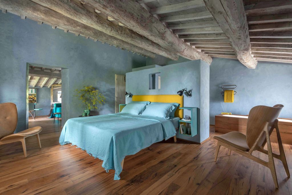 Suite mit Holzbalkendecke, blauem Bett und Holzböden