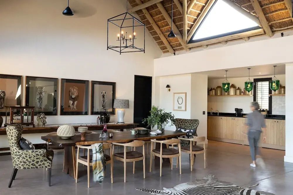 Helles Wohnzimmer mit langem Esstisch und moderner Beleuchtung im Monwana Hotel