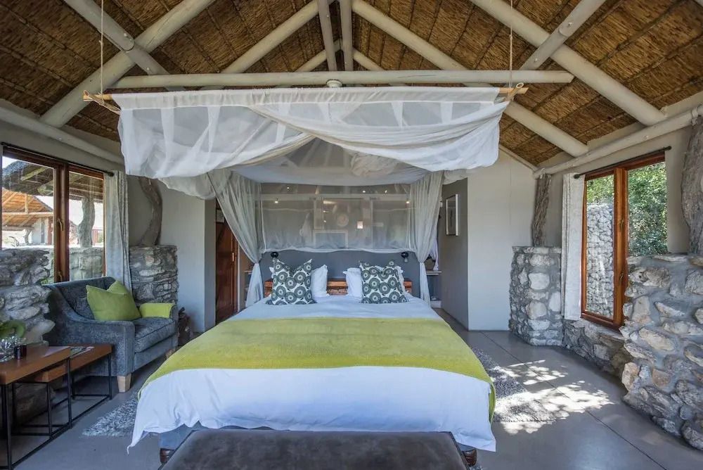 Luxus Suite mit Doppelbett und Baldachin unter einem strohgedeckten Dach