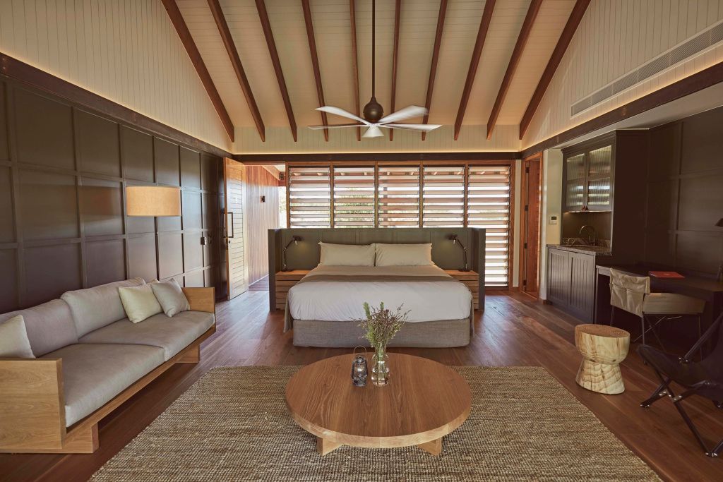 Elegantes Schlafzimmer mit Holzbalkendecke, modernem Doppelbett und Sitzecke