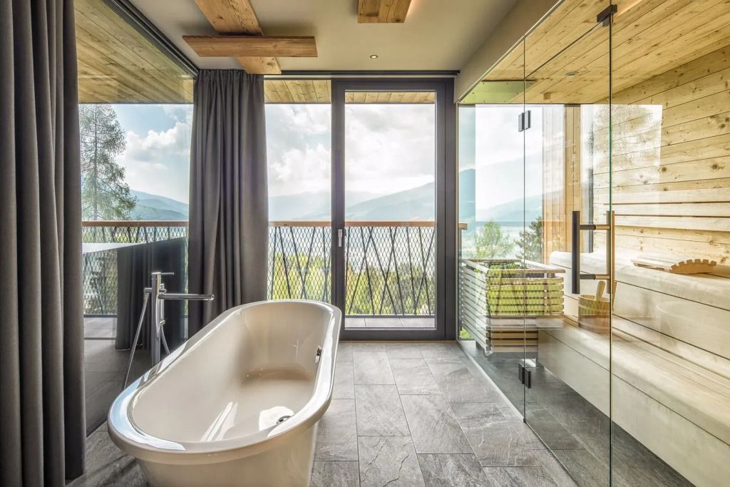 Freistehende Badewanne und Glasdusche mit Blick auf die Natur in der Treetop Suite