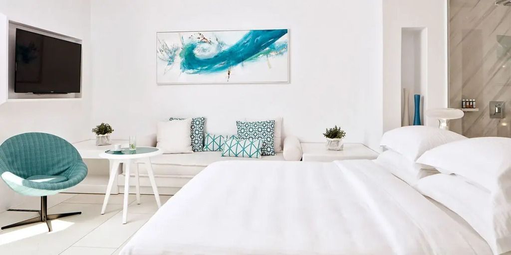 Helles Wohnzimmer mit abstrakter Kunst über dem Sofa und Akzentkissen in Blau- und Grüntönen.
