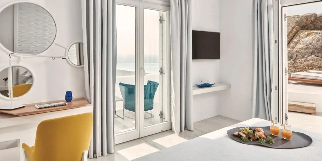 Zimmerblick aus dem Myconian Ambassador Hotel mit Balkon und blauem Stuhl