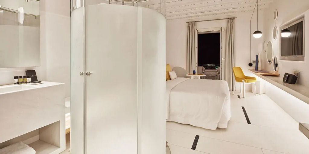Blick ins Zimmer mit abgerundeter Duschkabine und elegantem Bett