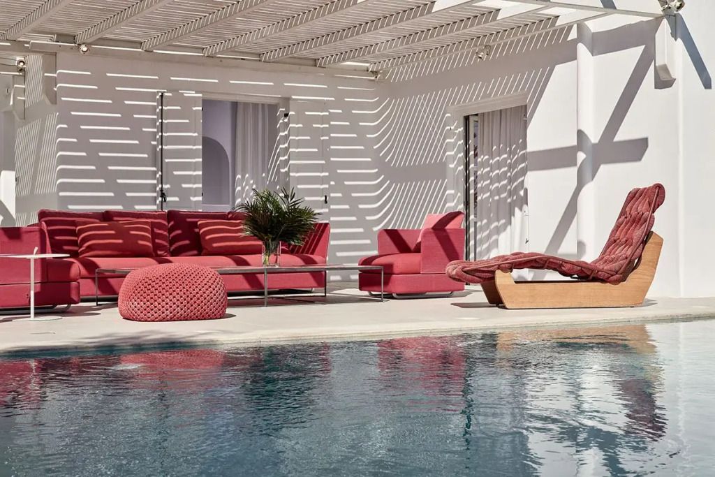 Moderne Terrasse mit roten Loungemöbeln und Pool im Sonnenschein.