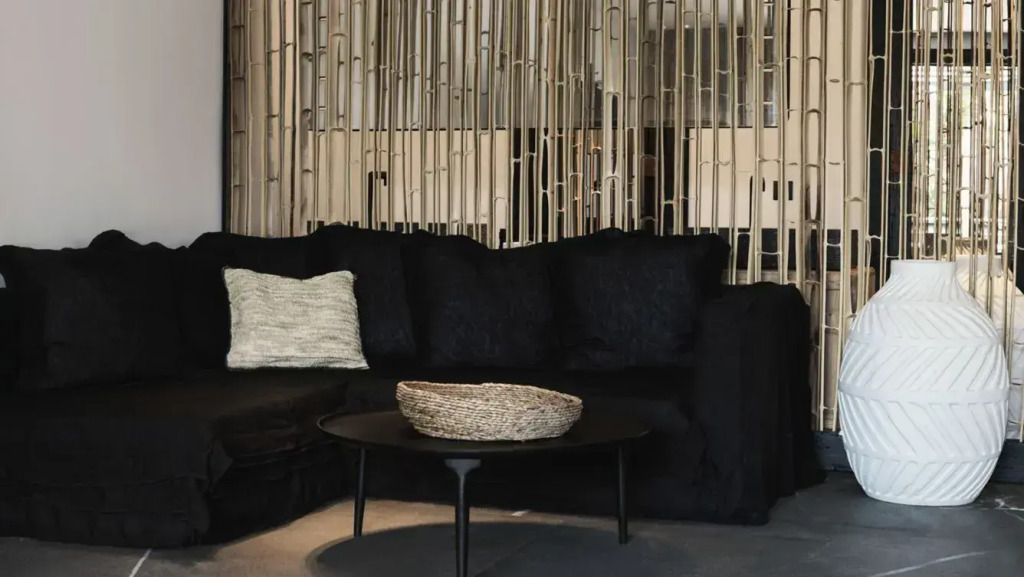 Gemütliche Lounge-Ecke mit schwarzem Sofa und Bambus-Dekor.