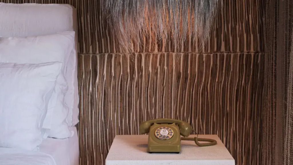 Vintage-Telefon auf einem Tisch vor einer texturierten Wand in einem Hotelzimmer