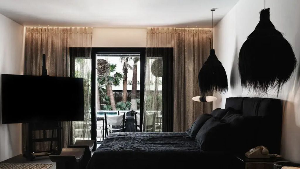 Schlafzimmer mit dunkler, stilvoller Einrichtung und Gartenblick