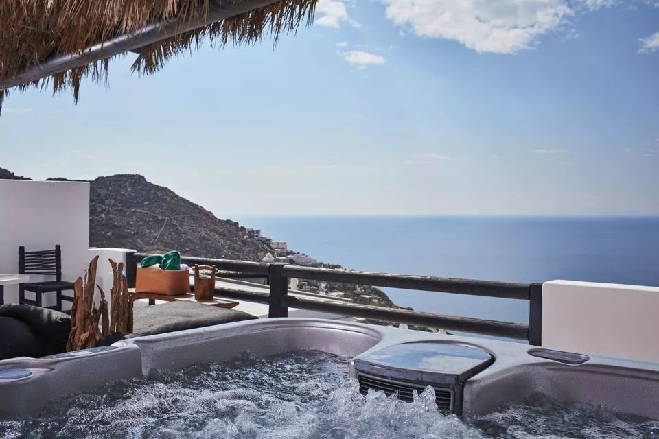 Outdoor-Whirlpool auf der Terrasse mit Blick auf das weite Meer und die Küstenlinie.