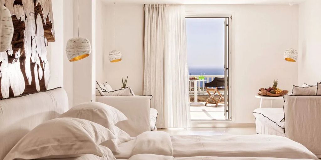 Helles Zimmer mit Doppelbett und Balkon mit Meerblick. Luftiges, elegantes Design.