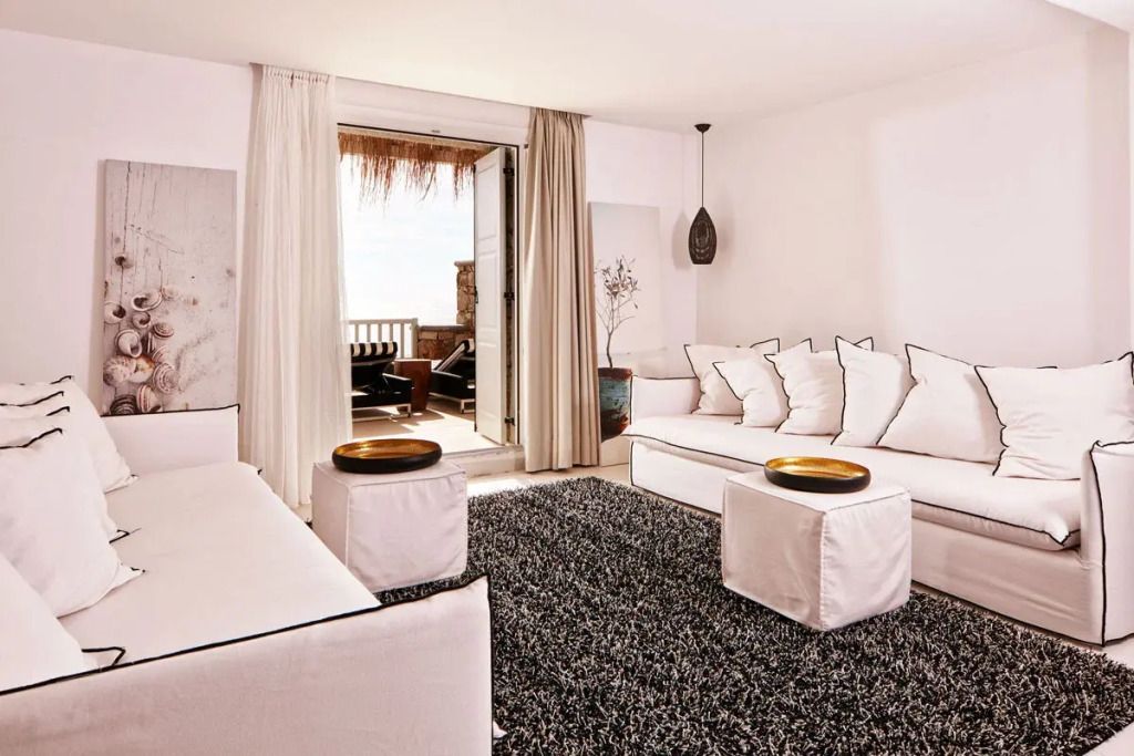 Wohnbereich mit gemütlichen Sofas und Zugang zu möblierter Terrasse mit Meerblick.